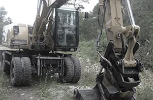 Hjulgrävare med redskapsfäste i skogsmiljö